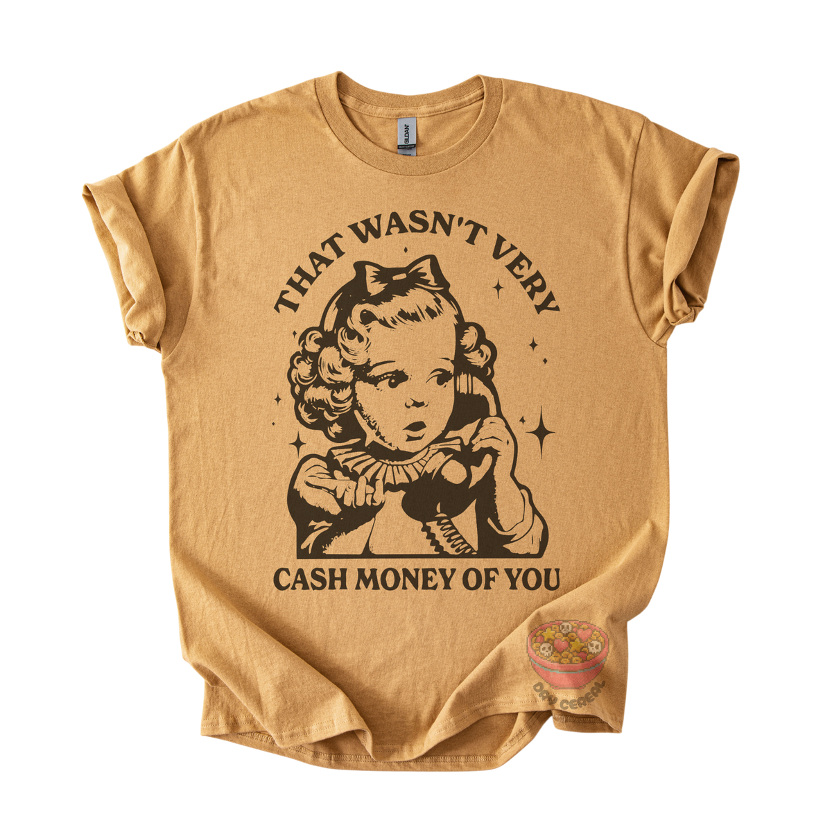 A tan graphic t-shirt featuring a vintage-style illustration of a young girl holding a telephone, with the text 'THAT WASN'T VERY CASH MONEY OF YOU' printed in black. 