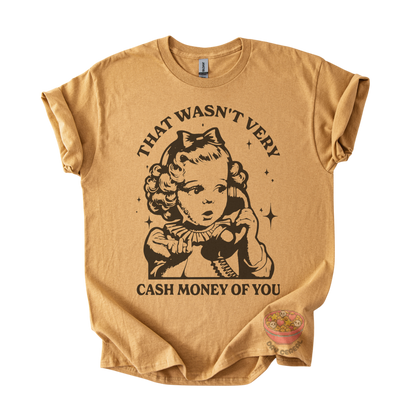 A tan graphic t-shirt featuring a vintage-style illustration of a young girl holding a telephone, with the text 'THAT WASN'T VERY CASH MONEY OF YOU' printed in black. 