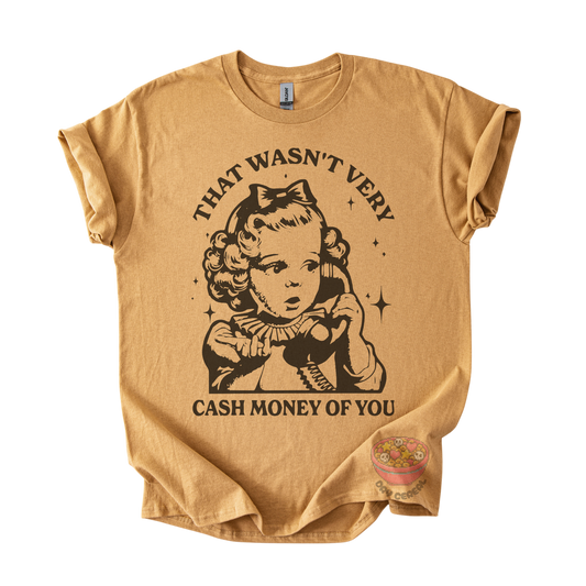 A tan graphic t-shirt featuring a vintage-style illustration of a young girl holding a telephone, with the text 'THAT WASN'T VERY CASH MONEY OF YOU' printed in black. 