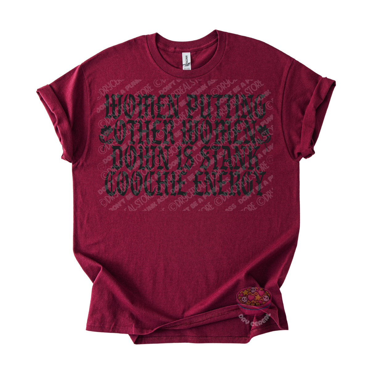 A maroon short-sleeve graphic t-shirt laid flat on a white background. The shirt features a distressed black text graphic reading 'WOMEN PUTTING OTHER WOMEN DOWN IS STAY COCHCHI ENERGY' across the chest.