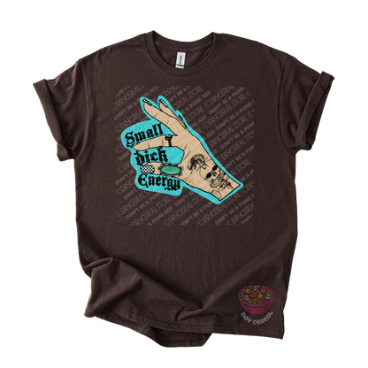 A dark brown graphic t-shirt featuring a hand graphic with the text 'Small Dick Energy' in teal and black.