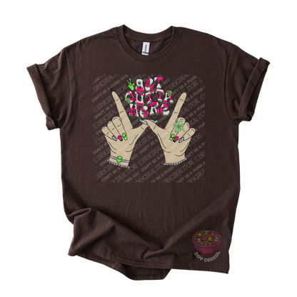 Dark brown unisex T-shirt featuring the phrase "Get Outta Here" above Y2K-inspired hands making the iconic gesture with colorful nails, alien accents, bracelets, and retro lettering.
