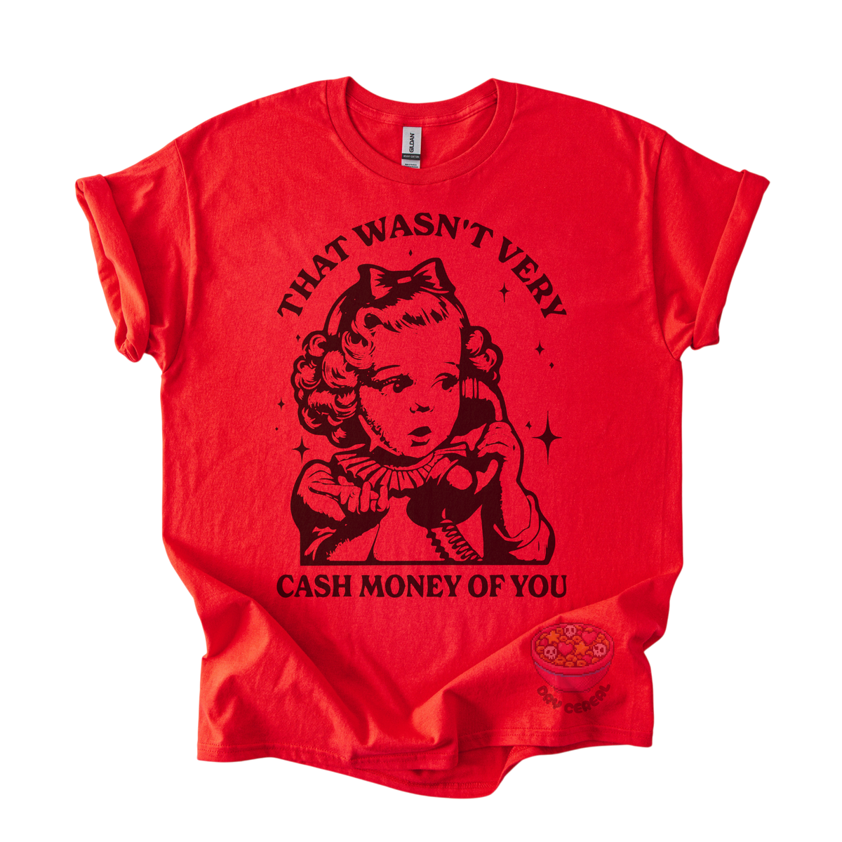 A bright red short-sleeve graphic t-shirt featuring a black vintage-style illustration of a young girl holding a telephone, with the text 'THAT WASN'T VERY CASH MONEY OF YOU' printed around the graphic. A small circular logo is visible near the bottom right hem.