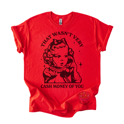 A bright red short-sleeve graphic t-shirt featuring a black vintage-style illustration of a young girl holding a telephone, with the text 'THAT WASN'T VERY CASH MONEY OF YOU' printed around the graphic. A small circular logo is visible near the bottom right hem.
