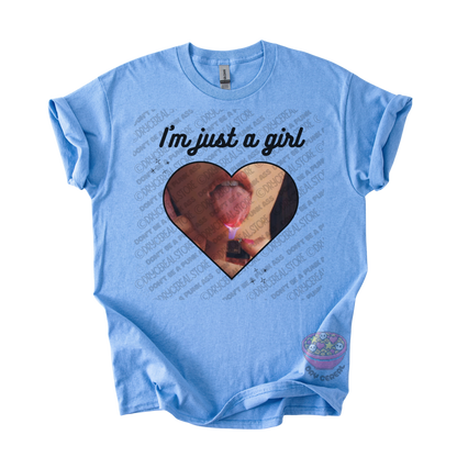 Light blue unisex T-shirt featuring the phrase "I'm just a girl" above an original heart-shaped collage graphic with an edgy alternative aesthetic