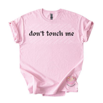 Light pink unisex tee featuring the phrase "don't touch me" in bold gothic black lettering across the chest.