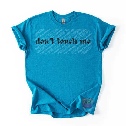 Teal unisex tee featuring the phrase "don't touch me" in bold gothic black lettering across the chest.