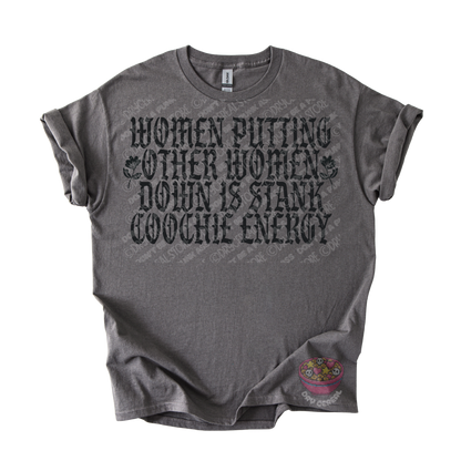 A dark gray heather graphic t-shirt featuring the text 'WOMEN PUTTING OTHER WOMEN DOWN IS STANK COOCHE ENERGY' in a distressed black font. The shirt is laid flat against a white background, with a small colorful graphic on the bottom right hem.