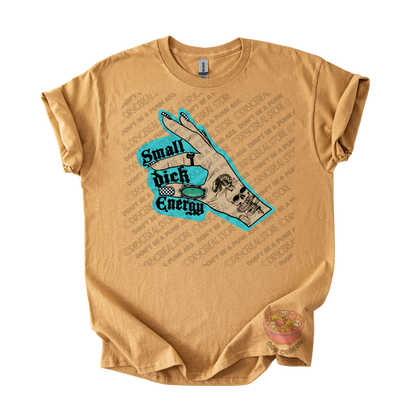 A tan graphic t-shirt featuring a hand illustration with a skull and the text 'Small dick Energy' in black