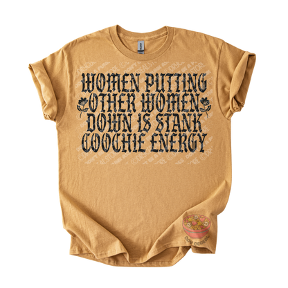 A tan short-sleeve graphic t-shirt laid flat on a white background. The shirt features a distressed black text graphic that reads 'WOMEN PUTTING OTHER WOMEN DOWN IS STANK COOCHE ENERGY' with small floral illustrations.