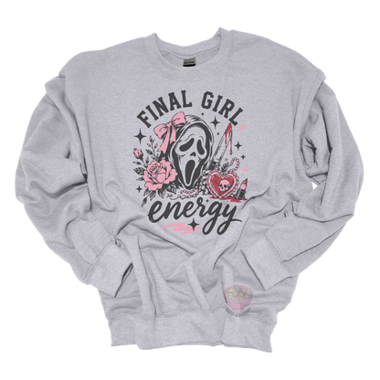 Gray crewneck sweatshirt featuring a horror-inspired ghost mask design with pink roses, a bloody knife, heart locket, lipstick, and the phrase "Final Girl Energy."