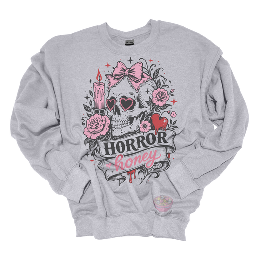 Light gray crewneck sweatshirt featuring a vintage skull with heart-shaped sunglasses, pink bow, roses, candle, dripping heart, and the phrase "Horror Honey" in a spooky gothic design.