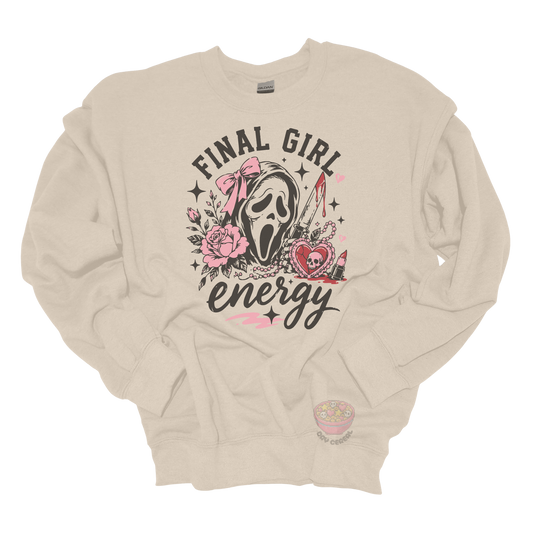 Beige crewneck sweatshirt featuring a horror-inspired ghost mask design with pink roses, a bloody knife, heart locket, lipstick, and the phrase "Final Girl Energy."