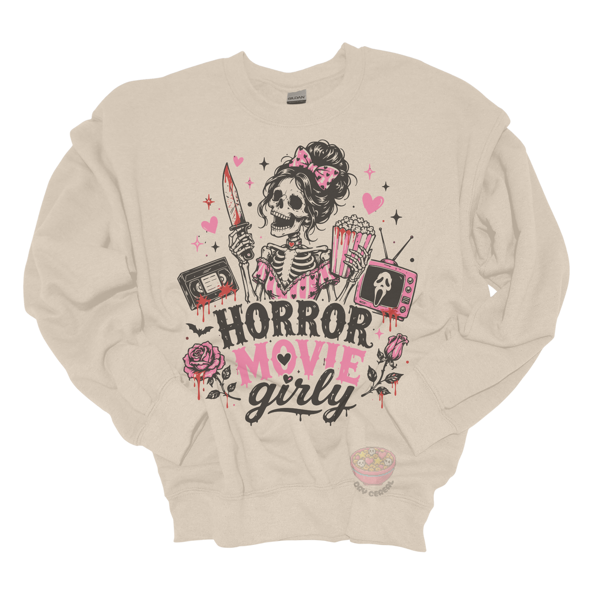 Beige crewneck sweatshirt featuring a skeleton with a pink bow holding a bloody knife and popcorn, surrounded by horror-inspired movie details, roses, hearts, a VHS tape, retro television, and the phrase "Horror Movie Girly."