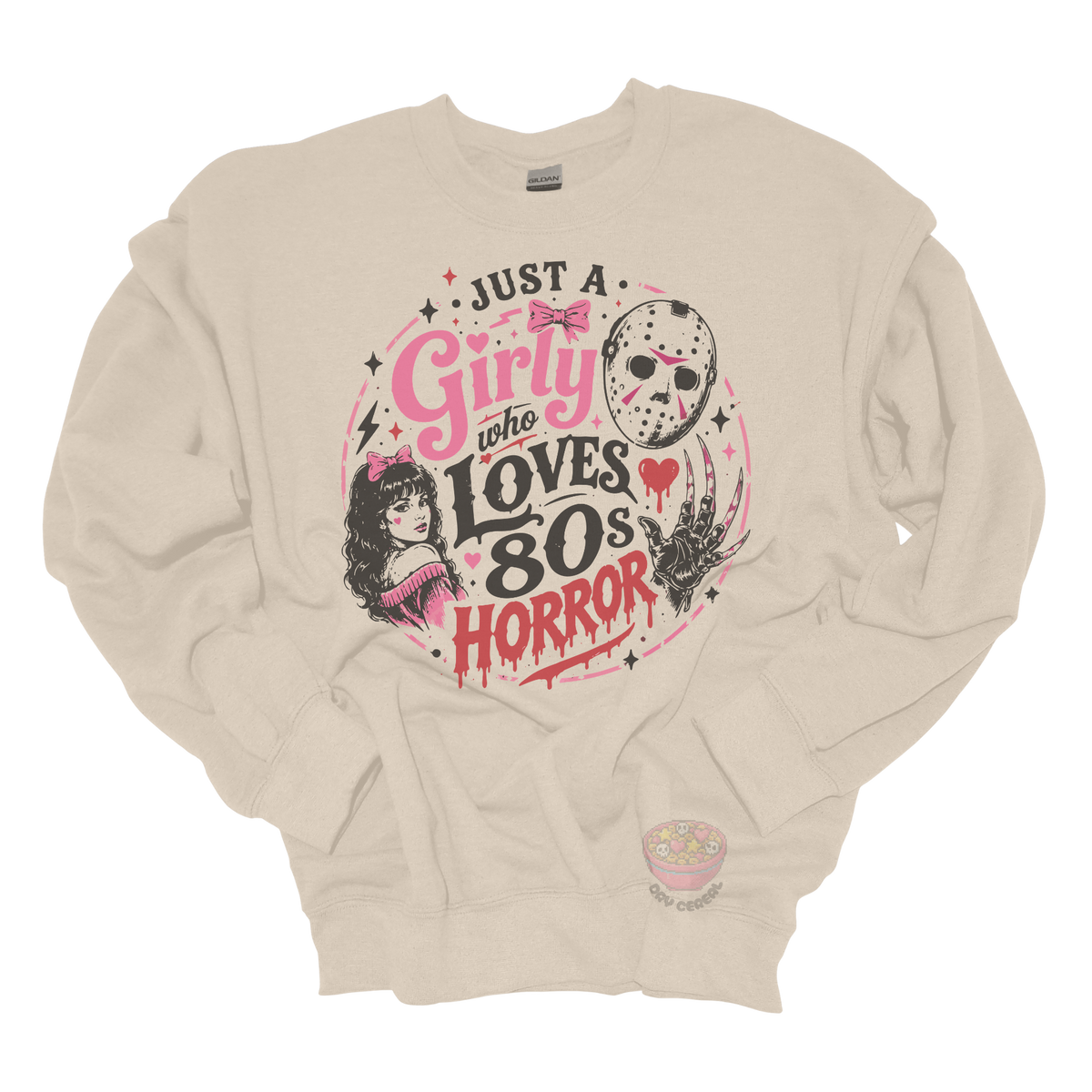 Beige crewneck sweatshirt featuring the phrase "Just a Girly Who Loves 80s Horror" with retro horror-inspired artwork including a hockey mask, clawed glove, vintage girl illustration, pink bows, and spooky accents.