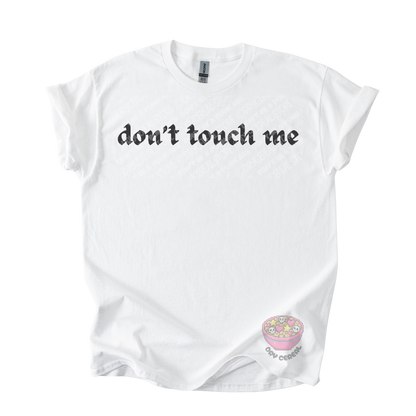 White unisex tee featuring the phrase "don't touch me" in bold gothic black lettering across the chest.