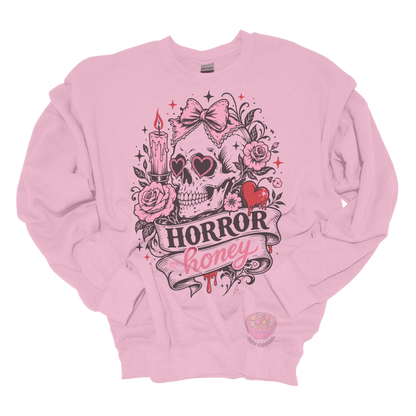 Light pink crewneck sweatshirt featuring a vintage skull with heart-shaped sunglasses, pink bow, roses, candle, dripping heart, and the phrase "Horror Honey" in a spooky gothic design.