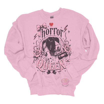 Light pink crewneck sweatshirt featuring a horror-inspired long-haired ghost emerging from a television, surrounded by pink bows, roses, pearls, lightning bolts, and the phrase "Horror Queen."