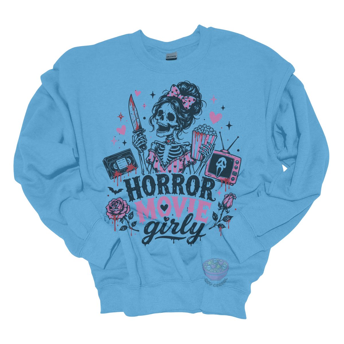 Light blue crewneck sweatshirt featuring a skeleton with a pink bow holding a bloody knife and popcorn, surrounded by horror-inspired movie details, roses, hearts, a VHS tape, retro television, and the phrase "Horror Movie Girly."