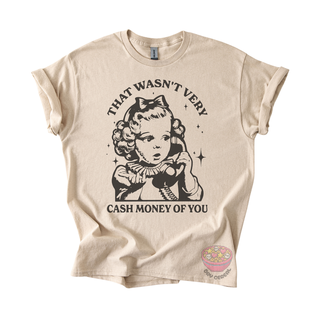 A beige graphic t-shirt featuring a black vintage-style illustration of a girl with a bow and the text 'THAT WASN'T VERY CASH MONEY OF YOU'. 