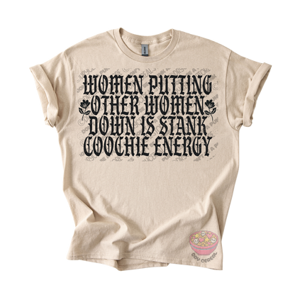 A beige graphic t-shirt with a black gothic-style text print reading 'WOMEN PUTTING OTHER WOMEN DOWN IS STANK COOCHE ENERGY'.