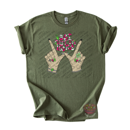 Olive green unisex T-shirt featuring the phrase "Get Outta Here" above Y2K-inspired hands making the iconic gesture with colorful nails, alien accents, bracelets, and retro lettering.