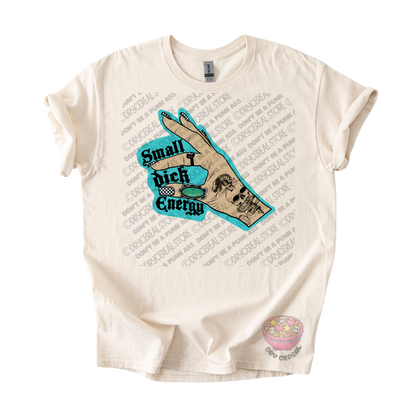 An off-white short-sleeve graphic t-shirt featuring a central design of a hand with a skull tattoo and a turquoise speech bubble that reads 'Small dick Energy'. 