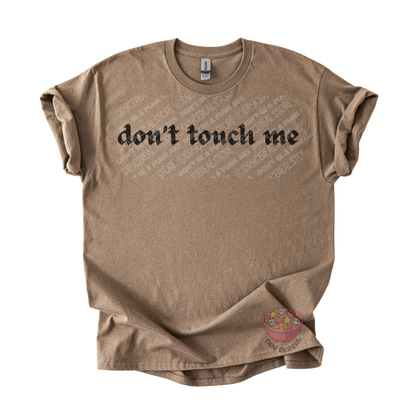 Light brown unisex tee featuring the phrase "don't touch me" in bold gothic black lettering across the chest.